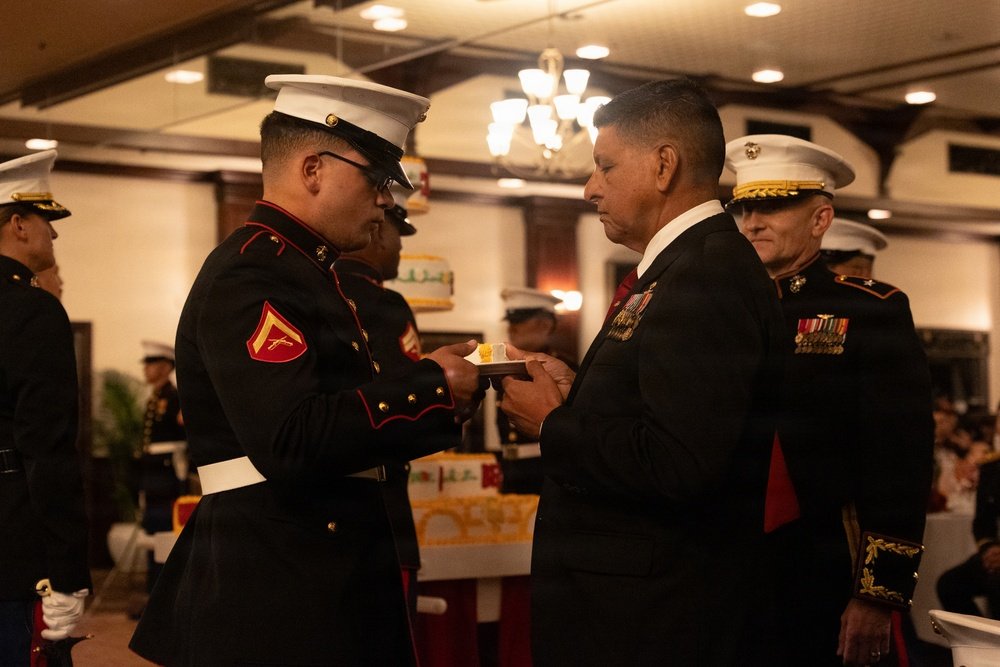 Oldest Marine passing birthday cake to the youngest Marine at a Marine Corps birthday ball